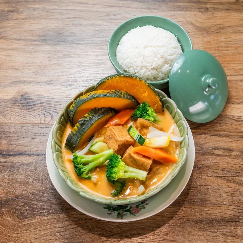 Thai pumpkin curry with tofu, broccoli, and carrots, served with a side of white rice.