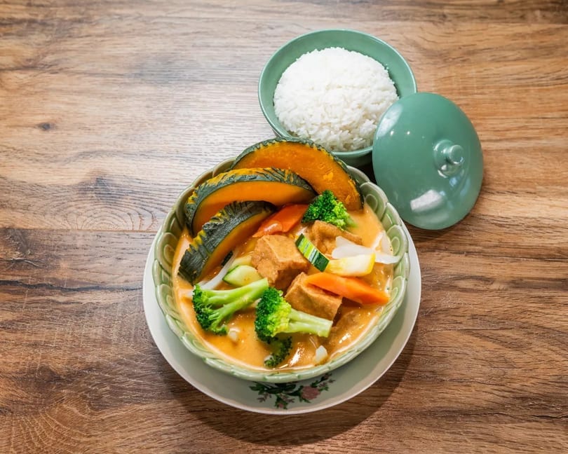 Thai pumpkin curry with tofu, broccoli, and carrots, served with a side of white rice.